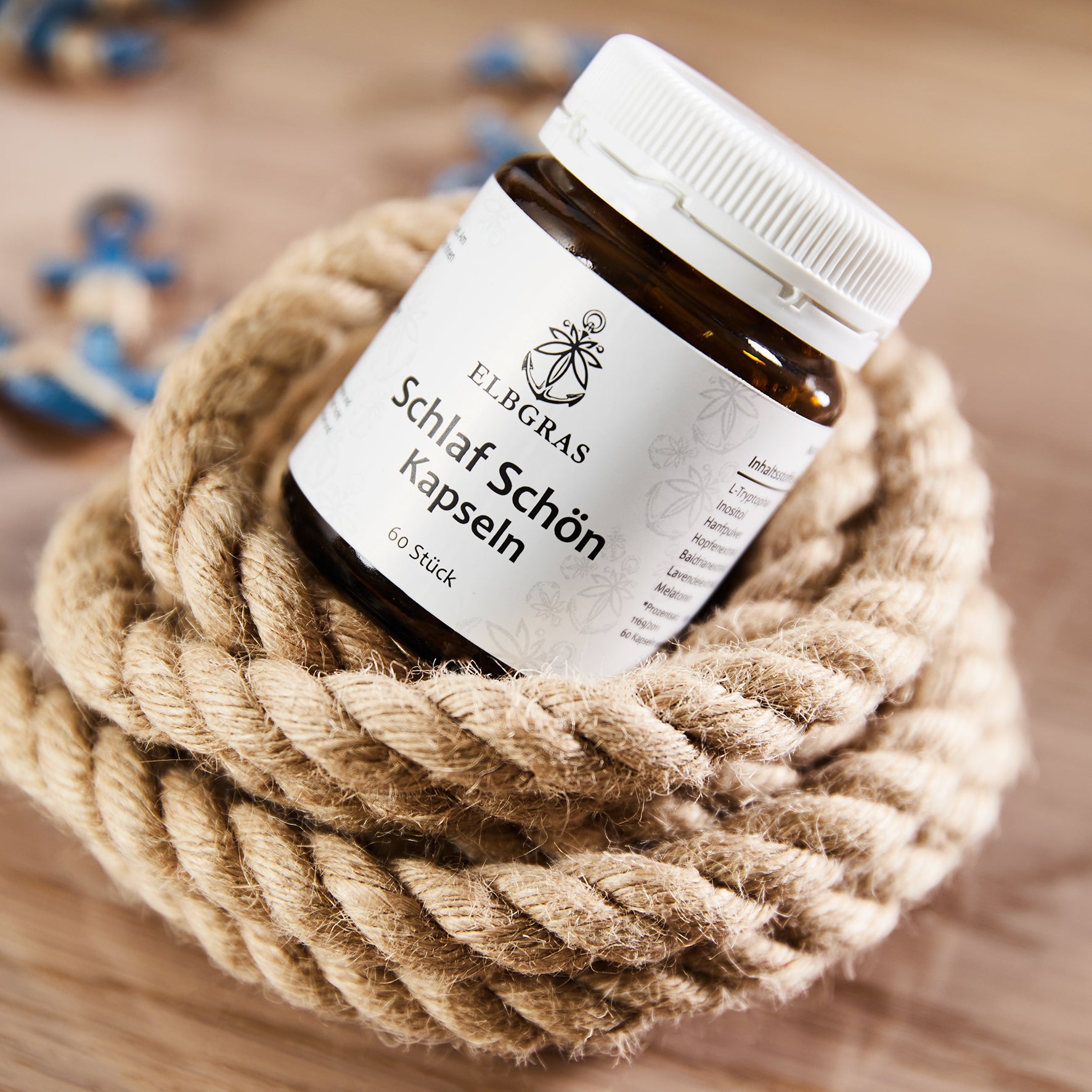 Braune Glasflasche Schlaf schön Kapseln mit weißem Schraubverschluss und schwarzem Textlabel auf dickem Naturseil liegend.